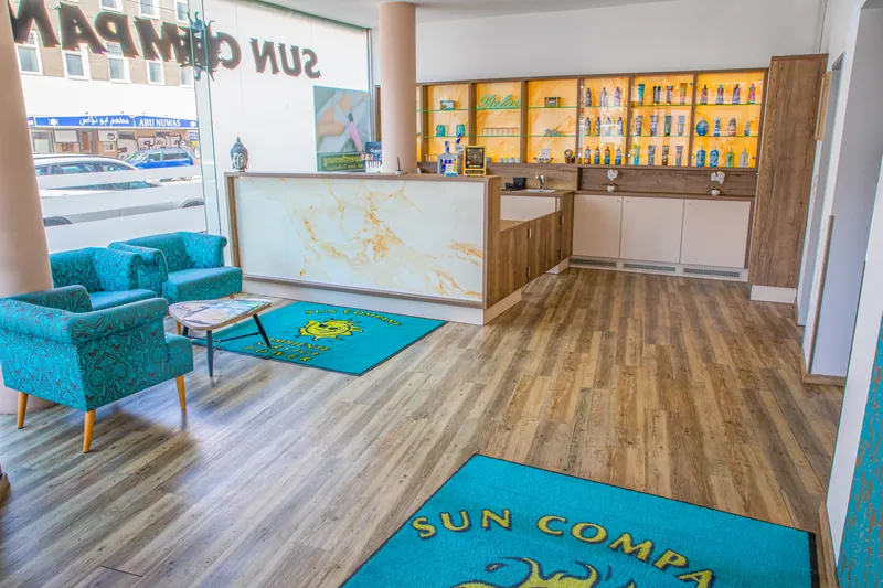 Recepcija Sun Company solarijuma sa mermernim pultom, tirkiznim foteljama, otiračima sa logom i policama sa proizvodima