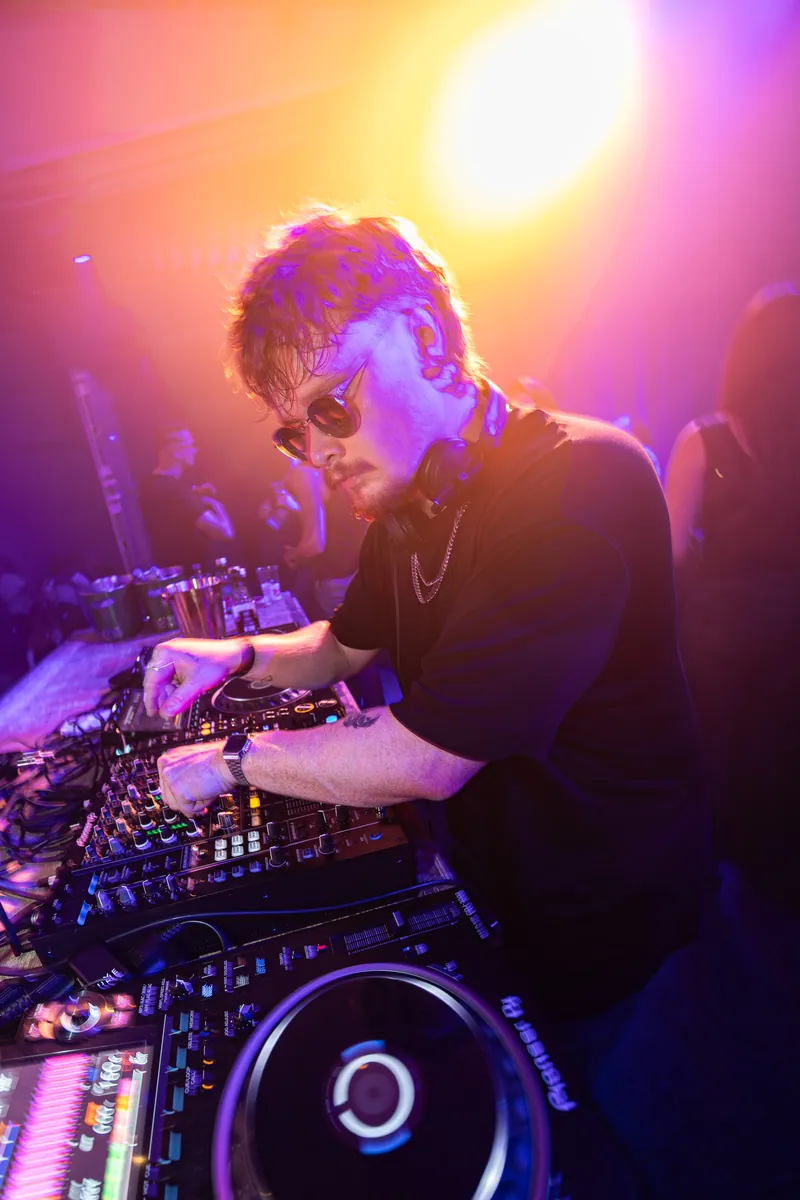 DJ za miksetom pod šarenim svetlima