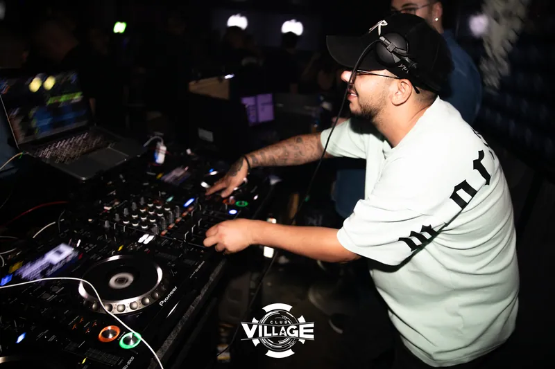 DJ sa crnom kapom i slušalicama pušta muziku za Pioneer pultom u Club Village